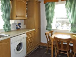 巴林罗布Delia's Cottage的厨房配有洗衣机和桌椅