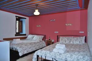 考克考利恩Tritoxo Guesthouse的红色墙壁客房的两张床