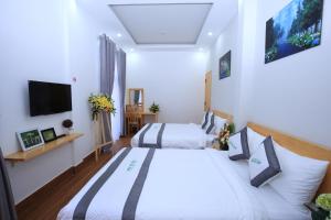 大叻Moc Tra Hotel的一间卧室配有两张床和一台平面电视