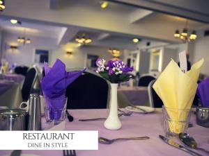 布莱克浦皇家波士顿酒店 的花瓶里装紫色花的桌子