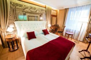 凯尔采GRAND HOTEL Kielce的卧室配有一张带两个红色枕头的大型白色床