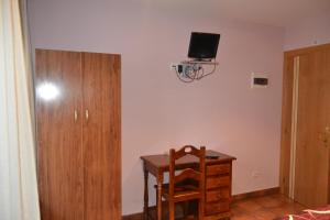 索里亚阿勒瓦科斯旅馆的客房设有一张桌子、一把椅子和一台墙上的电视