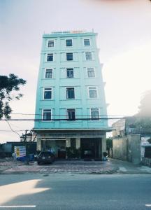 河静Thanh Binh Hotel的一座高大的蓝色建筑,前面有一辆汽车