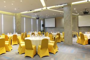 泗水耶穆尔萨利黄釉酒店 的一间会议室,配有桌子和黄色椅子