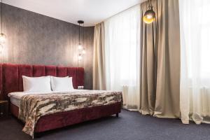 彼尔姆新星酒店的一间卧室配有一张带红色床头板和窗帘的床