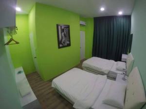 古晋齐妮亚度假屋的一间设有两张床和绿色墙壁的客房