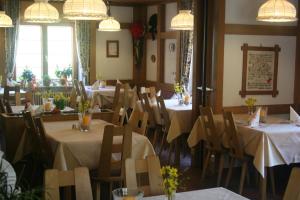 托特瑙希斯申酒店的餐厅配有桌椅和白色桌布