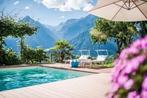 思科纳Haus Artus的一个带遮阳伞和椅子的游泳池以及山脉