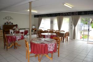 楚梅布Travel North Guesthouse的餐厅设有桌椅,配有红色和白色的桌布