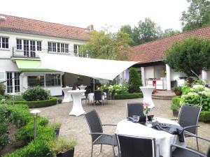 BomlitzGästehaus Villa Wolff的一座配有白色桌椅的庭院和一座建筑