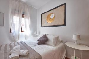 托莱多ToledoRooms Estrella - M, L, XL, XXL - Pisos con Azotea - Sun Terrace的白色的卧室配有一张床,墙上挂着一幅画