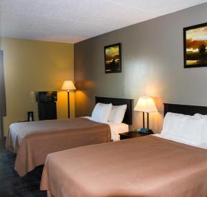 LakotaSunlac Inn Lakota的酒店客房设有两张床和两盏灯。