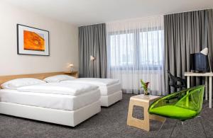 美因河畔法兰克福法兰克福温德姆特里普酒店的酒店客房,设有两张床和一把绿色椅子