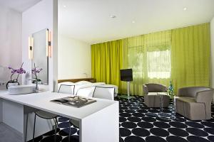 美因河畔法兰克福法兰克福温德姆特里普酒店的客厅配有白色的柜台和绿帘