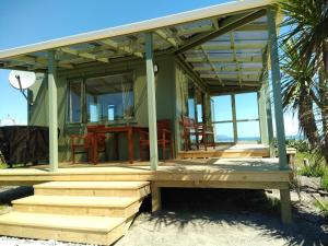 Cape FoulwindOkari Cottage的海滩上的房子,配有桌椅