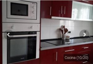 托里代巴拉Casa _pareada con piscina y jardin privado的厨房配有红色橱柜、炉灶和微波炉
