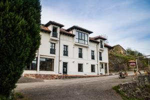 坎加斯-德奥尼斯Hotel Montañas de Covadonga的街上的白色房屋,设有黑窗