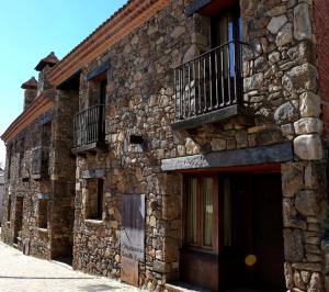 洛索亚河畔布伊特拉戈Estrella rural casa rural en la Sierra de Madrid的一座石头建筑,旁边设有阳台
