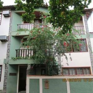 CambuciPousada Beija Flor的绿色和白色的建筑,前面有一棵树