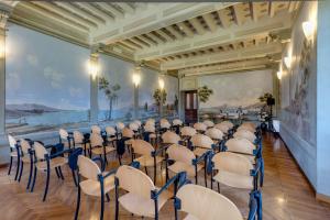 佛罗伦萨拉斯特拉别墅酒店的一间房间,里面摆放着一排椅子和一幅画作的墙壁