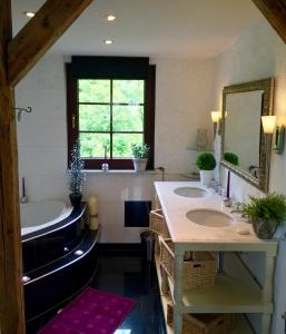 坎普-博尔恩霍芬Villa Christina的浴室设有2个水槽、浴缸和镜子