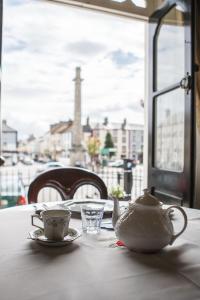 比尔埃米顿酒店的桌子上带茶壶和杯子,桌子上带有窗户