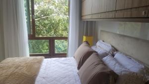 佩德拉阿祖尔Loft luxo em Pedra Azul的卧室配有带枕头的床铺和窗户。