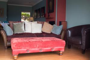 哈特比斯普特Annie's Boutique Guesthouse and Garden Spa的客厅配有红色的沙发和两把椅子