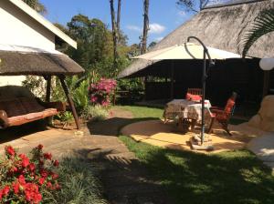 绍斯布鲁姆Tropical Paradise的天井配有桌子和遮阳伞,还种植了鲜花