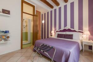 维罗纳Giardino Giusti House & Court的一间卧室配有紫色床和紫色条纹墙