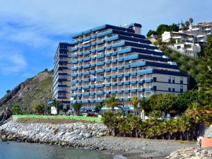 阿尔姆尼卡Arrayanes Playa Almuñecar的水体旁的山丘上的建筑物