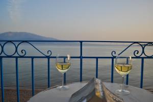 纳弗帕克托斯Villa "Pietra e Mare"的两杯白葡萄酒坐在桌子上,俯瞰水面