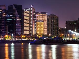 迪拜班达阿炎罗塔纳 - 迪拜河酒店的城市天际线,夜晚在水中划船