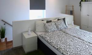 塞瓦尔兴Ferienwohnung in Seewalchen的一间白色卧室,配有床和床头柜