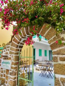 罗德镇Galanopetra RHODES GREECE的拱门,上面有粉红色的花和桌椅