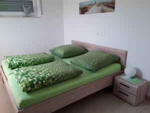 佩讷明德Haus am Leuchtfeuer的一张带绿色床单和枕头的床