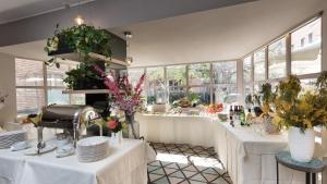 米兰伦巴蒂雅酒店的餐厅设有白色的桌子和鲜花