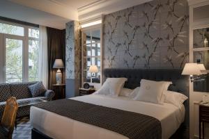马德里Relais & Châteaux Heritage Hotel的一间卧室配有一张大床和一把椅子