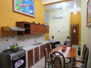 伊基托斯Alojamiento El Cardenal的一间带炉灶和桌子的厨房,并有客人坐在房间内