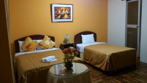 特鲁希略Hotel Plaza Trujillo的酒店客房设有两张床和一张桌子。