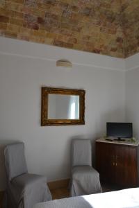 马泰拉San Biagio Materapartment的卧室配有两把椅子和一面墙上的镜子