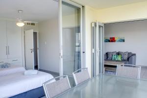 德班14 Kyalanga - by Stay in Umhlanga的卧室设有床和椅子,铺有玻璃地板