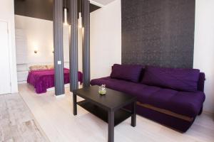 哈尔科夫Sumskaya ApartHotel的客厅配有紫色沙发和床。