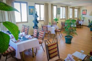 亚的斯亚贝巴Union Hotel Apartments的一间设有白色桌椅的餐厅,种植了植物
