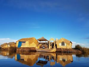 普诺Uros Lake Titicaca Lodge的水中一群小屋和一艘船