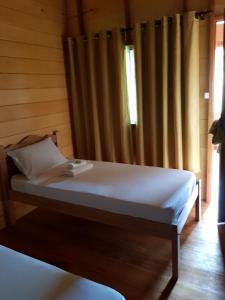 Careiro亚马逊金龙鱼小屋旅馆的一间卧室配有床和带窗帘的窗户