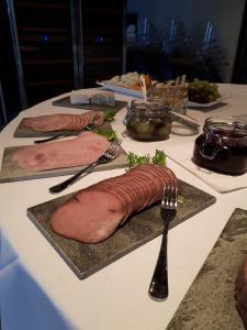 奥普达尔Bjerkeløkkja Bed and Breakfast的一张桌子,上面有三盘肉和叉子