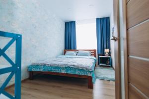 苏梅Vip apartmen Harkovskaya的一间卧室配有一张带蓝色窗帘的床和一扇窗户