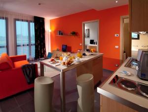 维贡扎Matrix Hotel & Residence的带橙色墙壁的厨房和客厅