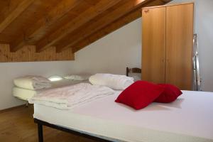 Ponte CaffaroCasa Ornella的一间卧室配有两张带白色床单和红色枕头的床。
